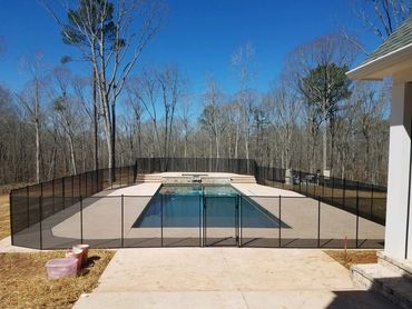 Outdoor swimming pool enclosed by a black safety fence.