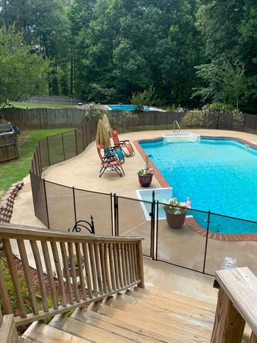 A fenced backyard pool area with lounge chairs and potted plants.