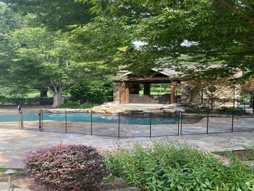 A serene backyard with a fenced pool and lush greenery.