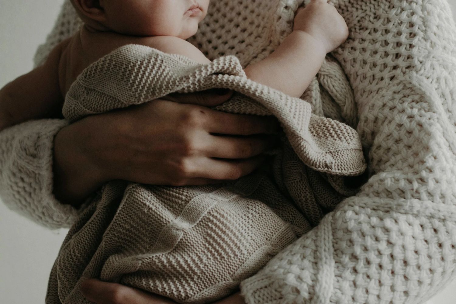 New baby in blanket being held by breastfeeding mother 