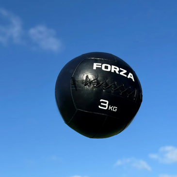 A black FORZA 3kg medicine ball against a blue sky.