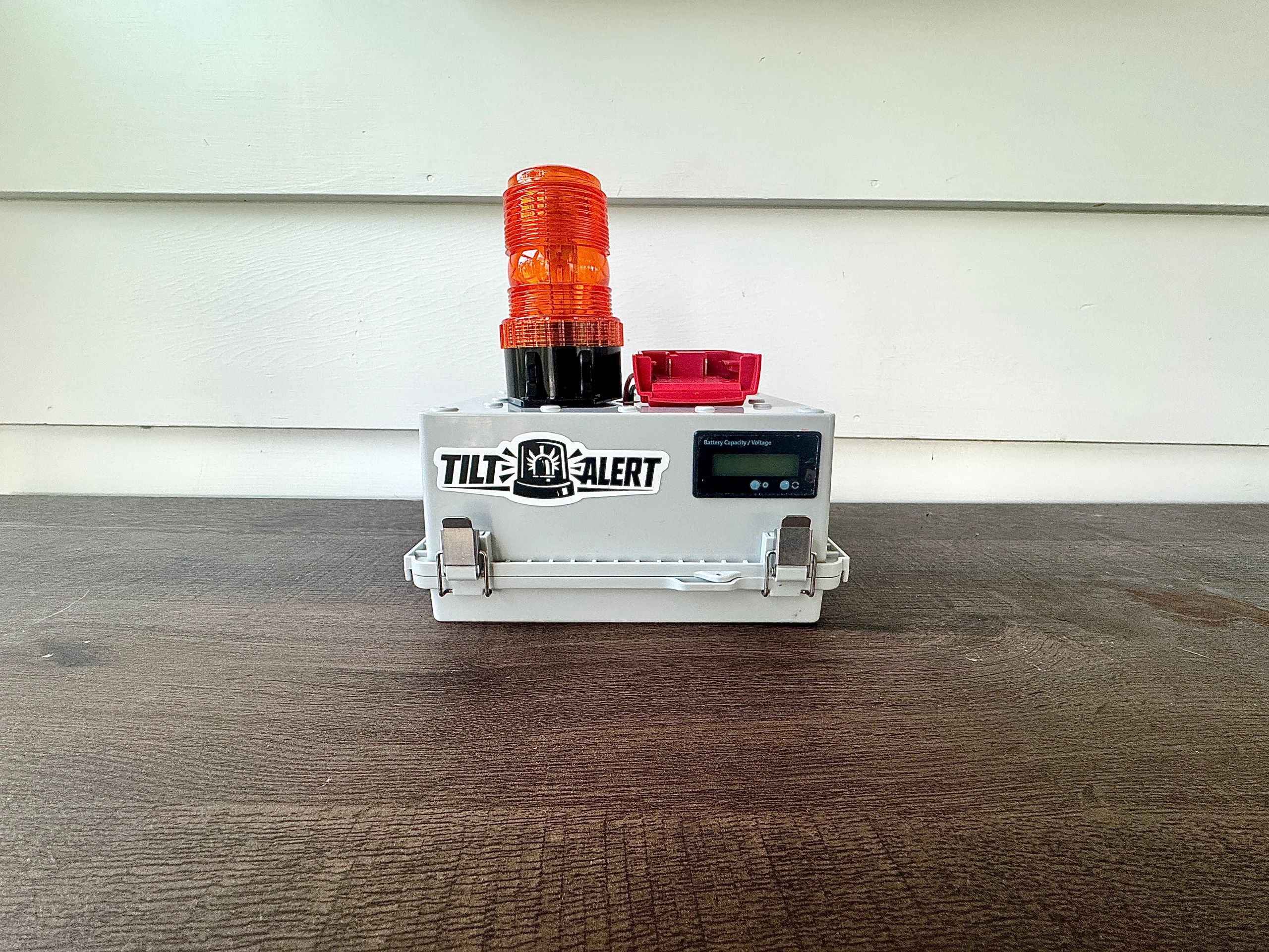Tilt Alert device with orange warning light on a wooden surface.