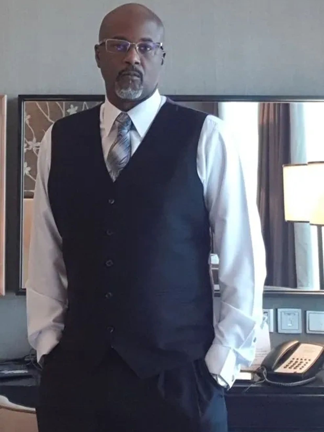 Man in formal attire standing confidently indoors.