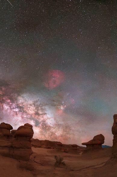 Starry night sky over rocky desert landscape.