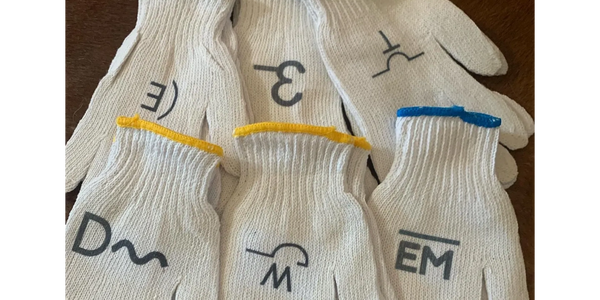 Six pairs of white work gloves with colored cuffs and markings on the back.