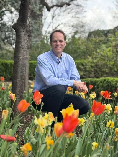 Man sitting in a colorful flower garden.