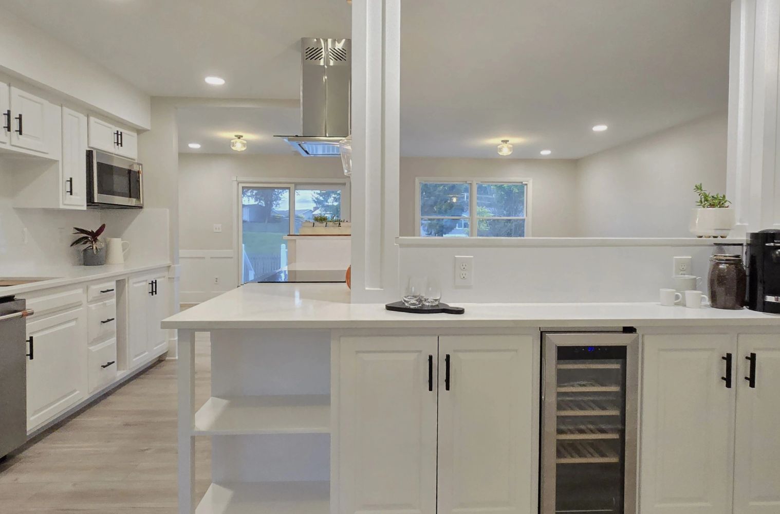 Modern white kitchen with island and wine fridge.