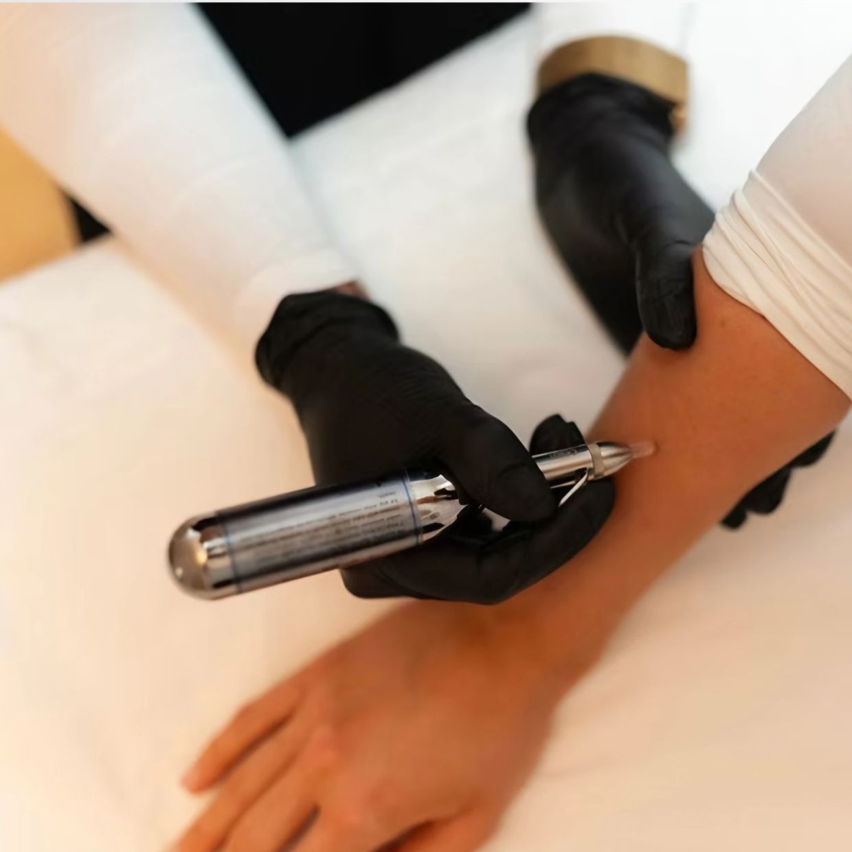 Close-up of a gloved hand administering an injection to an arm.