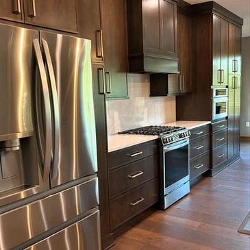 Modern kitchen with stainless steel appliances and dark wood cabinets.