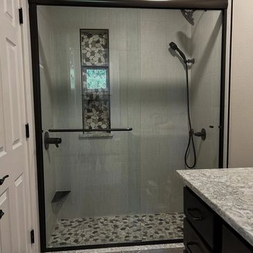 Modern bathroom shower with black-framed glass door.