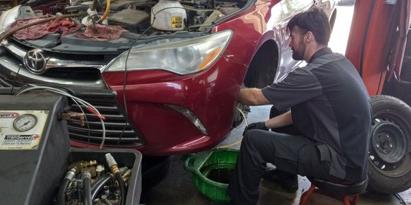 Mechanic working on a red car's wheel in a garage.