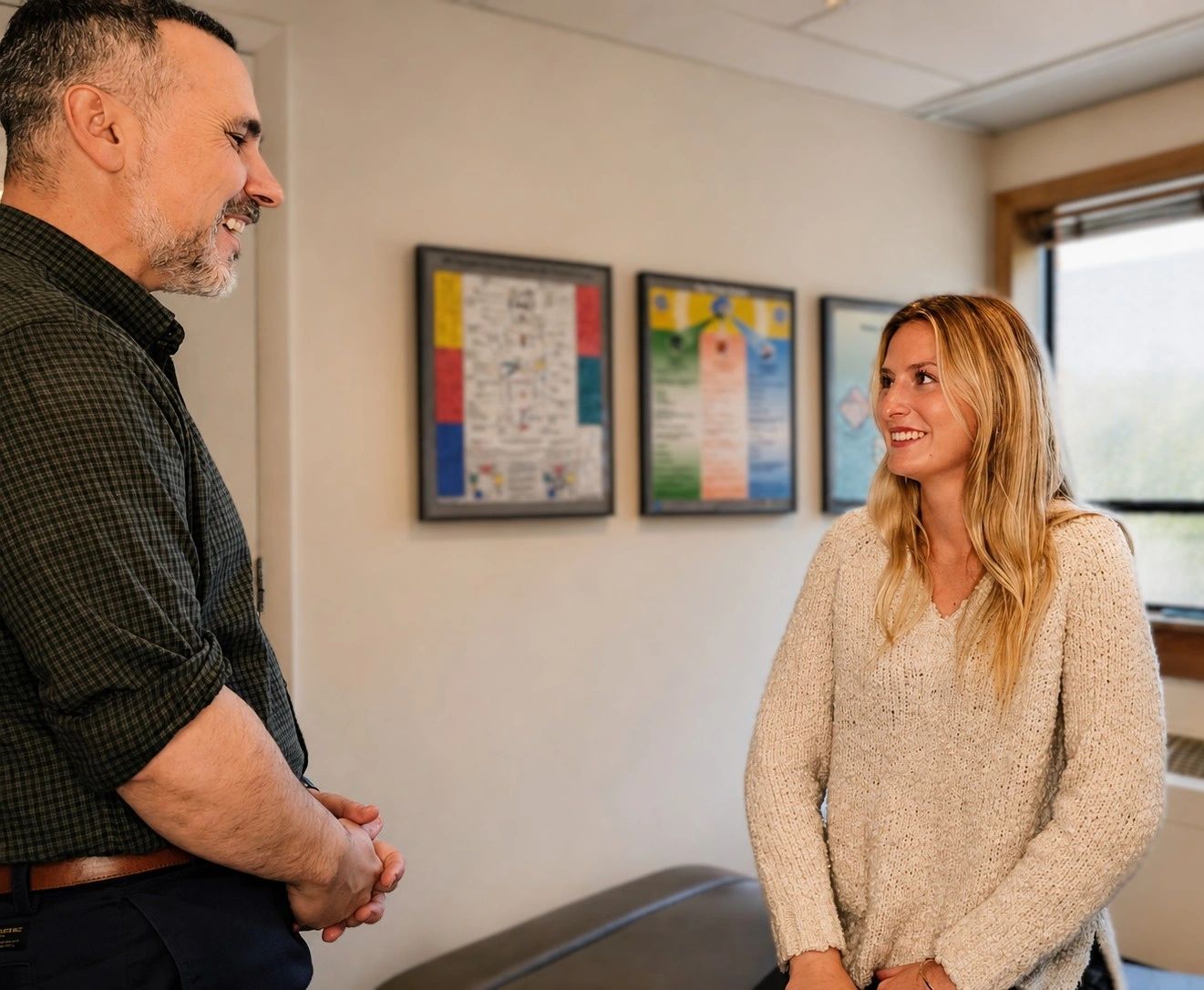 Chiropractor smiling and talking with a patient standing in the treatment room