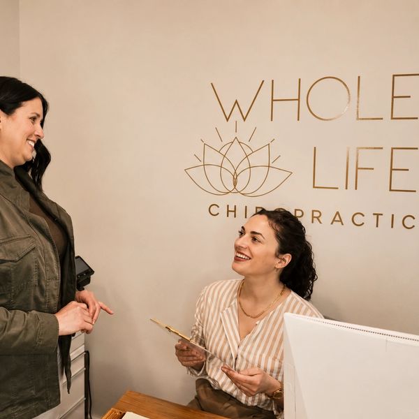 Vanessa chatting at the front desk of Whole Life Chiropractic
