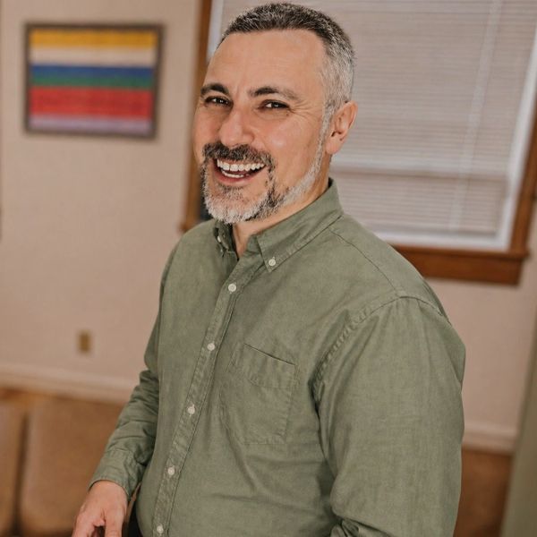 A chiropractor smiles in the clinic, reflecting a warm and patient-centered approach.