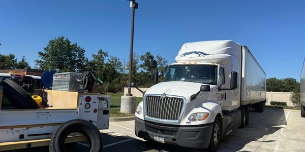 White semi-truck parked in a lot on a sunny day.