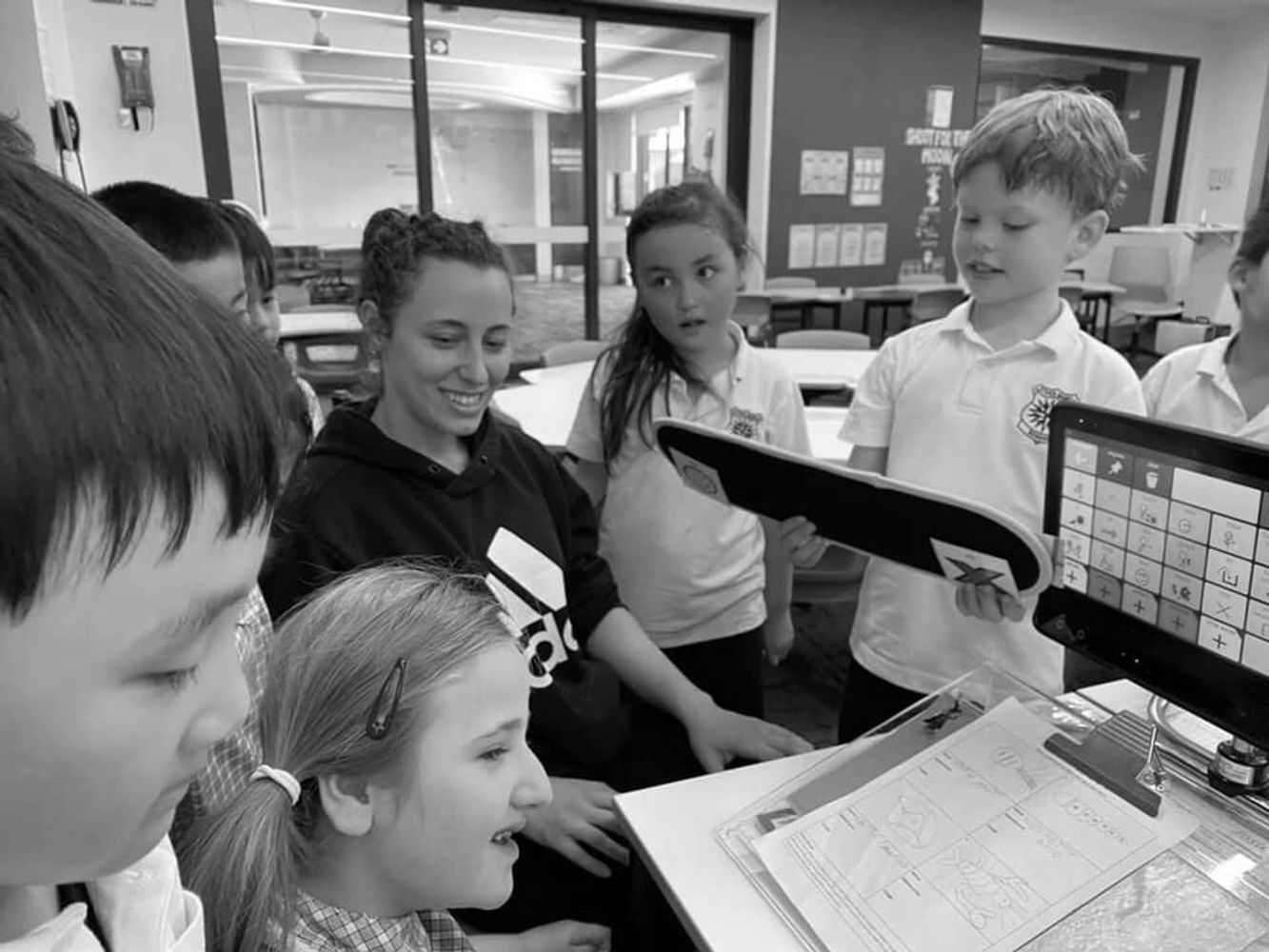 A teacher and students using a communication board and TobiiDynavox eye gaze device during class.