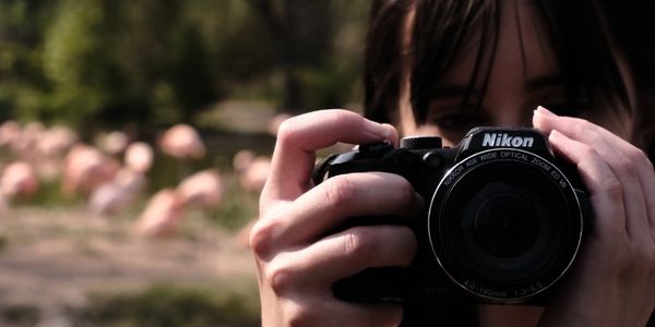 Owner holding a Nikon camera ready to take a photo outdoors.