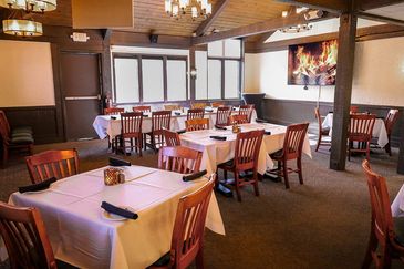 Cozy restaurant dining area with wooden furniture and white tablecloths.