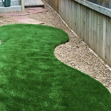 Artificial grass, surrounded with decorative rock and stepping stones.