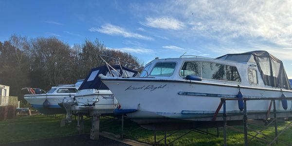 Several boats are docked on stands outdoors under a blue sky.