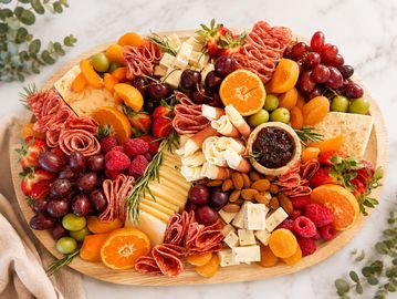 A colorful platter of assorted meats, cheeses, fruits, and nuts.