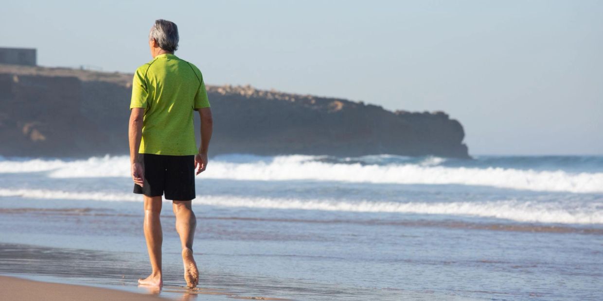 Older man walking alone along the beach, reflecting on life and the journey ahead