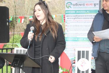A woman speaking into a microphone at an outdoor event.