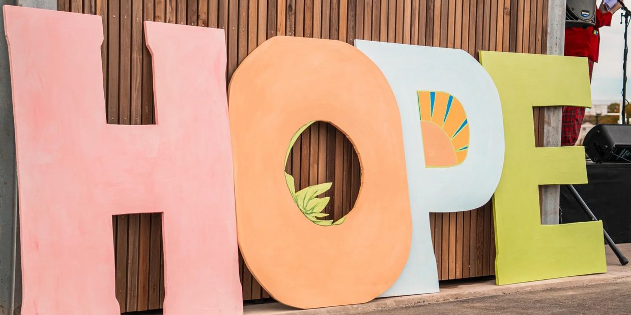 Large colorful letters spelling 'HOPE' against a wooden wall.
