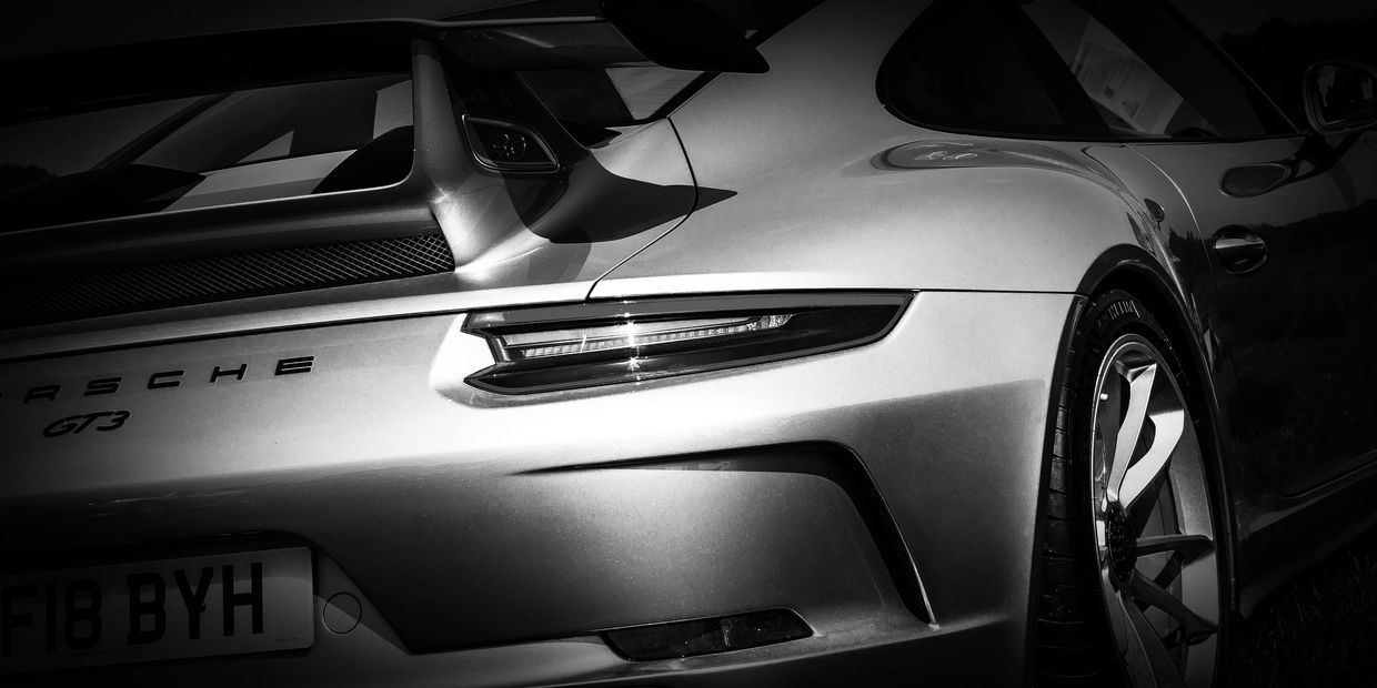 Close-up of a Porsche GT3 rear in dramatic black and white lighting.