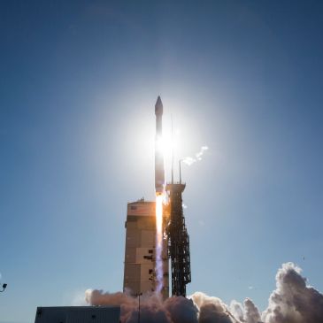 A rocket launches into a clear blue sky.