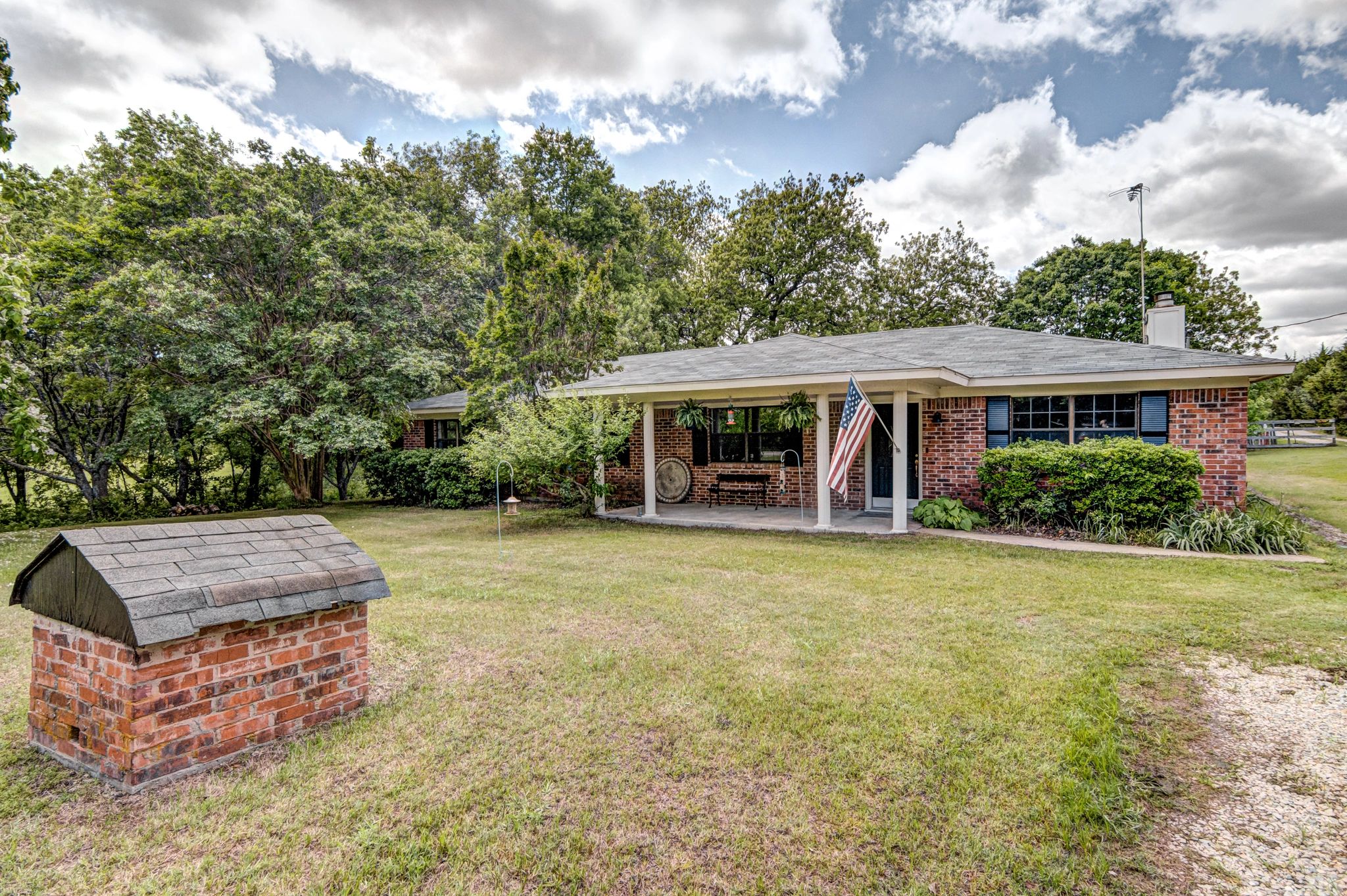 Single-story brick house with a lawn and American flag.