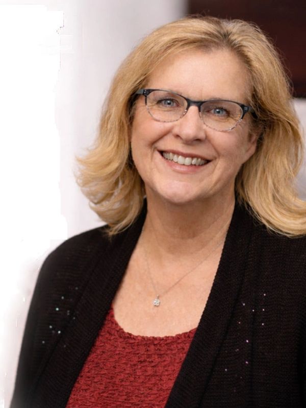 Smiling woman with glasses and blonde hair wearing a red top and black cardigan.