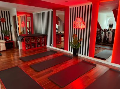 A modern fitness studio with red lighting and yoga mats.