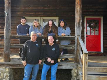 Group photo on a wooden porch with a red door.