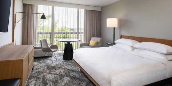 Modern hotel room with large bed and seating area.