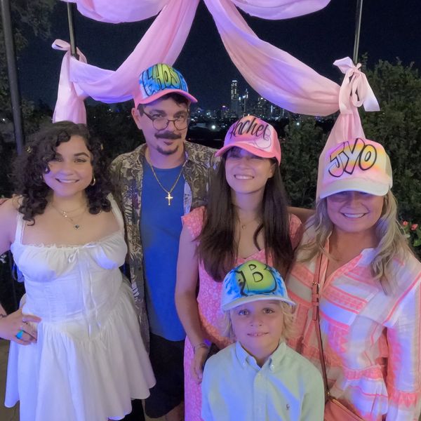 Group of five people smiling under pink drapes at night.