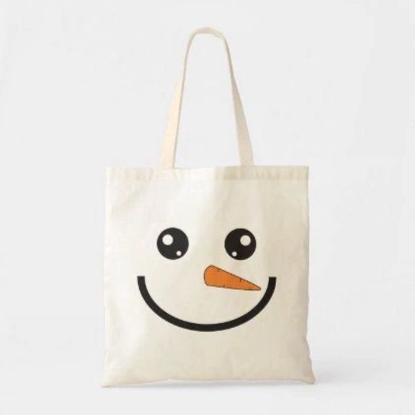 Beige tote bag with a cute snowman face design featuring black eyes and an orange carrot nose.