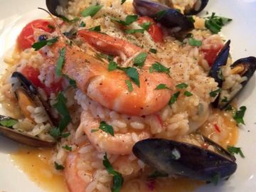 Seafood risotto with shrimp, mussels, tomatoes, and fresh herbs, served in a rich, creamy sauce.