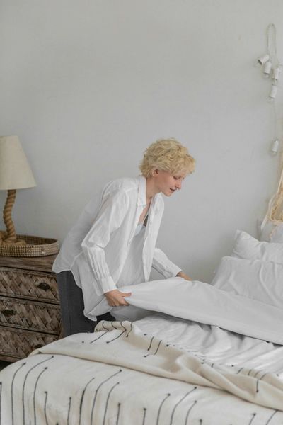 Woman finishing touches on making the bed in the morning. 