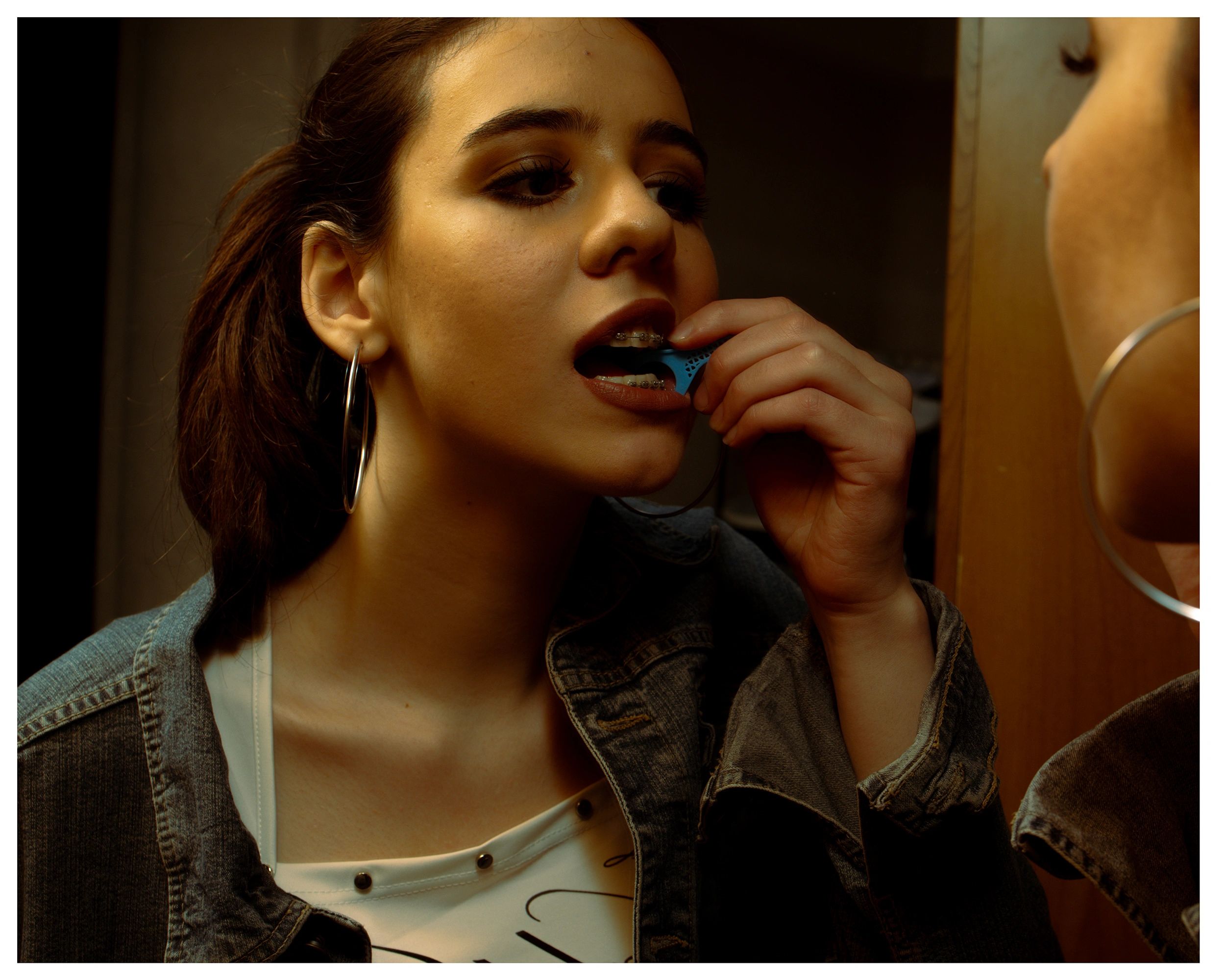 Woman flossing braces in front of mirror.