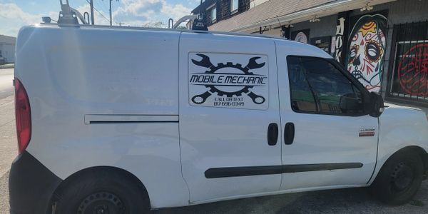 White van with Mobile Mechanic logo and contact info parked on the street.