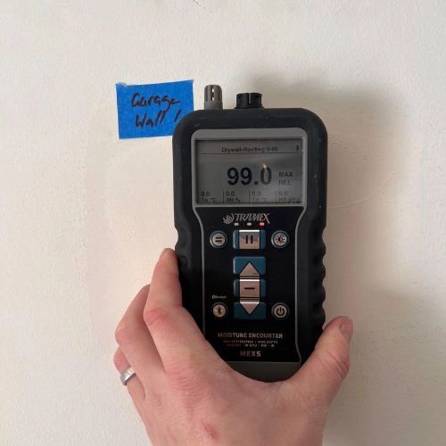 Moisture meter showing high water damage reading on garage wall. Moisture meter showing high water damage reading on garage wall.
