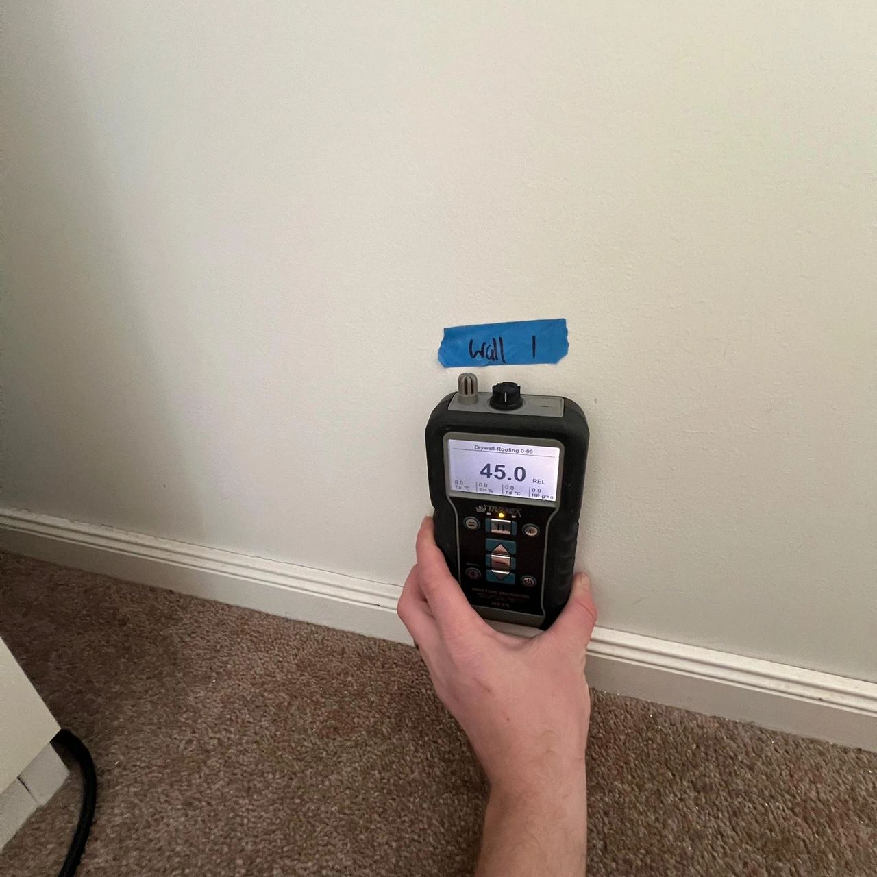 Moisture meter reading water damage levels on interior wall.