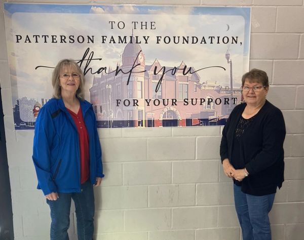 Two women standing beside a thank you banner.