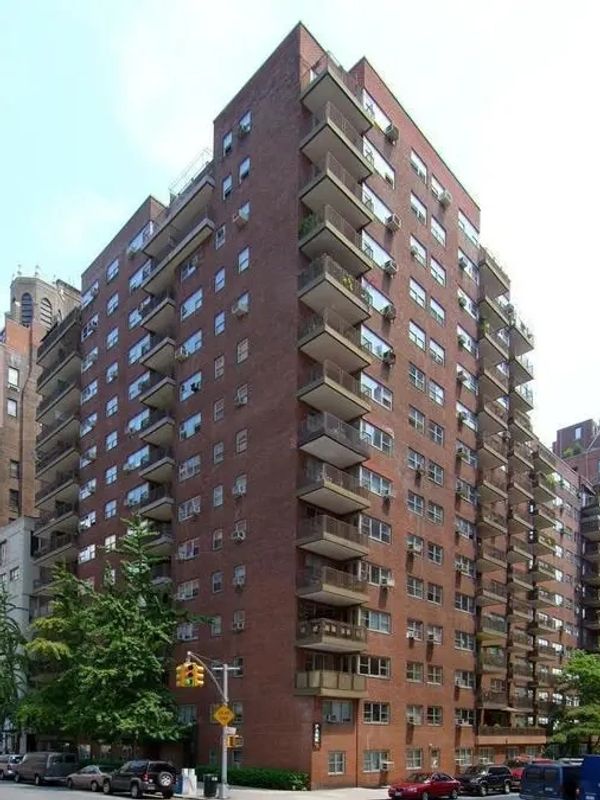 Tall brick apartment building with balconies in an urban setting.