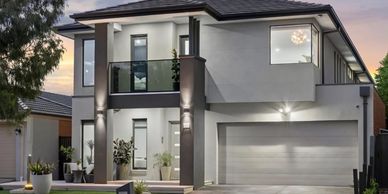Modern two-story house with sleek design and large windows at dusk.