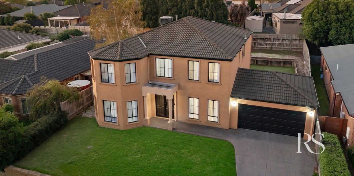 Large two-story brick house with a black tiled roof and spacious green lawn.