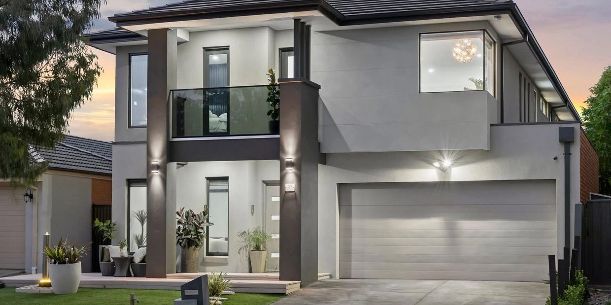 Modern two-story house with large windows and a double garage at dusk.