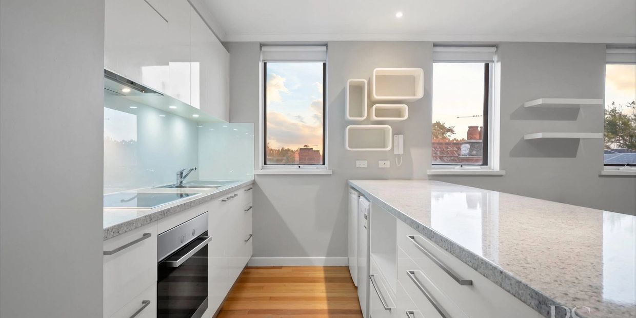 Modern white kitchen with sleek cabinetry and large windows.