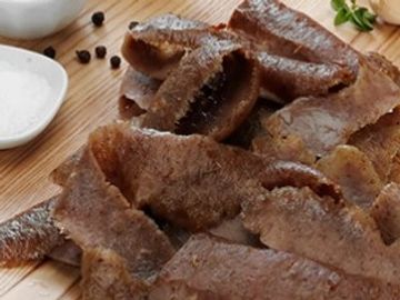 Close-up of cooked beef liver pieces on a wooden board.